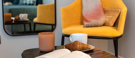 A cozy reading nook with a small table, a book, a croissant, and a mug.
