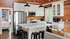 A modern kitchen with white cabinets, stainless steel appliances, and a central island with stools.