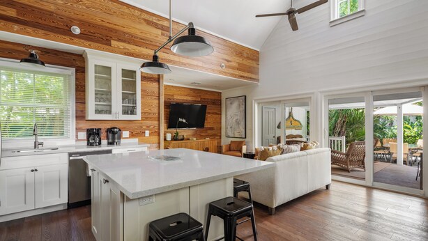 A spacious kitchen with a large island, wooden ceiling, and a dining area with outdoor seating.