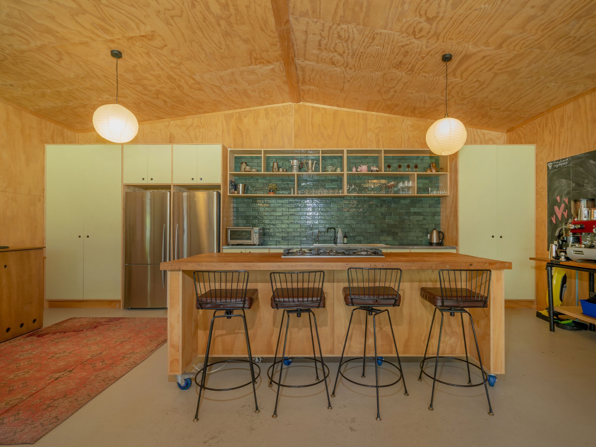 A kitchen with a central island, bar stools, stainless steel appliances, and wooden cabinetry.