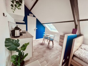 Un apartamento moderno y funcional con kitchenette, comedor con mesa y sillas, y zona de descanso con cama.