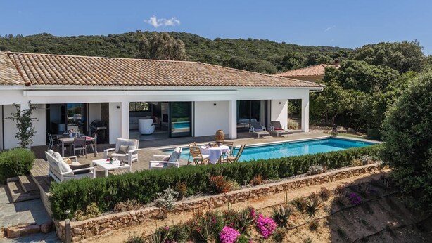 Una casa moderna con piscina, mobiliario exterior y jardín.