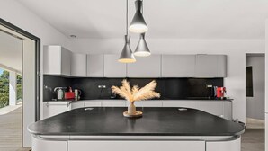 Una cocina moderna con una isla curva, iluminación colgante y un jarrón decorativo.