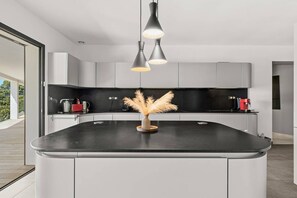 Una cocina moderna con una isla curva, iluminación colgante y un jarrón decorativo.