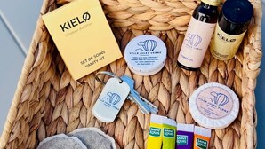A wicker basket containing a vanity kit with a set of keys, a bottle of shower gel, a bottle of liquid soap, and several tubes of body wash.
