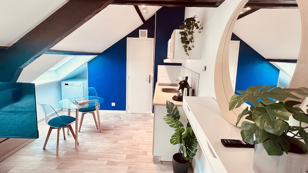 A modern loft apartment with a dining area, kitchen, and a large mirror.