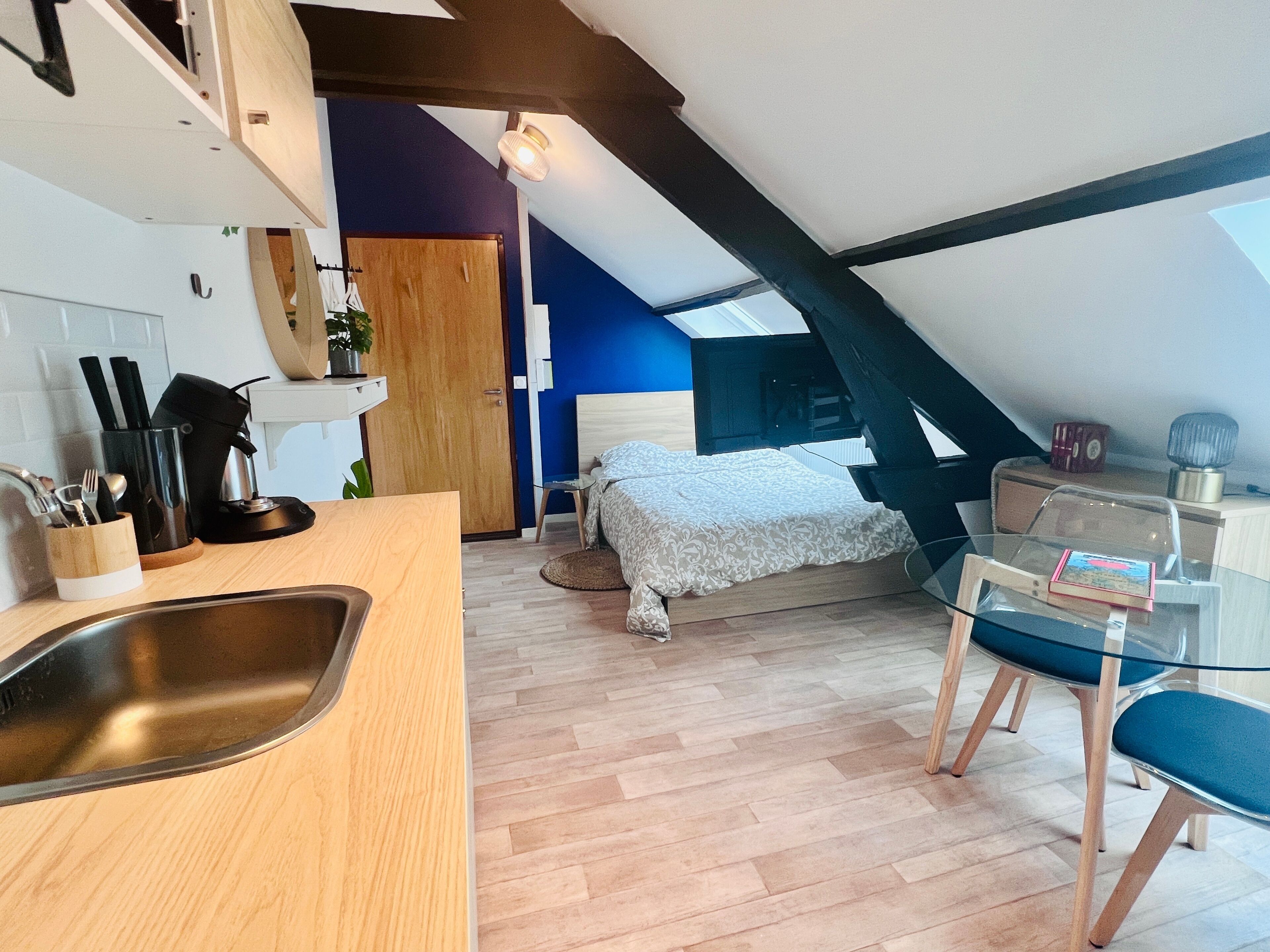 A compact room with a kitchenette, a bed, a desk, and a chair.