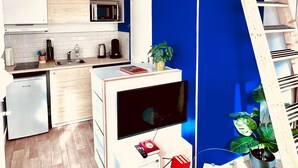 A compact kitchen with modern appliances, a built-in TV, and a small dining area. - De la Terre à la Lune (Amiens)