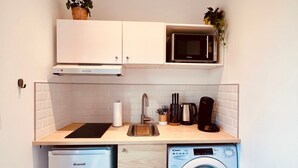 A compact kitchen with a dishwasher, washing machine, microwave, and a sink. - L'Ile Mystérieuse - Studio avec Terrasse (Amiens)