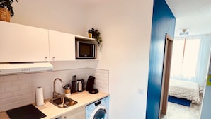 A compact kitchen with a microwave, sink, and washing machine. - L'Ile Mystérieuse - Studio avec Terrasse (Amiens)