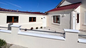 A white building with a red roof, a white door, and two windows with wooden frames. - Tour du monde en 80 jours - Studio avec Terrasse (Amiens)