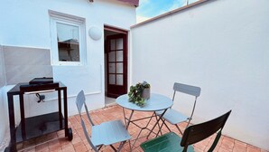 A small patio with a table and chairs, a potted plant, and a window with a view. - Tour du monde en 80 jours - Studio avec Terrasse (Amiens)