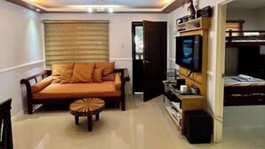 Una sala de estar con un sofá, televisor y una pequeña mesa.