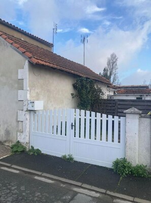 Una propiedad residencial cerrada con techo de tejas, cerca blanca enrejada y muro de concreto.
