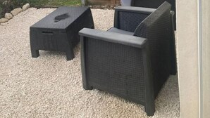 Un patio con mobiliario exterior, una parrilla y un cerco de madera.
