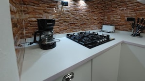 Cucina con piano cottura a gas, macchina per il caffè e forno a microonde.
