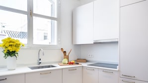 A modern kitchen with white cabinets, a stainless steel sink, and a window with a view of buildings. - Adriano 2.1 by Home at Homes (Sevilla)