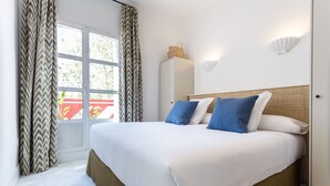 A neatly made bed with a white and brown headboard, a bedside basket, and a wall-mounted shell decoration. - Adriano 2.1 by Home at Homes (Sevilla)