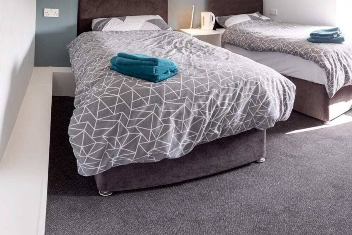 A hotel room with two beds, a nightstand, and a window.