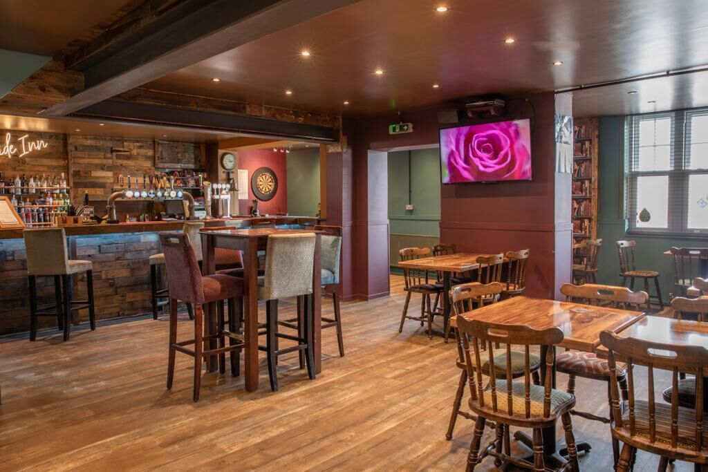 Un rincón acogedor de bar con muebles de madera, una barra y una televisión mostrando una rosa.