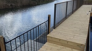 Eine Holzterrasse mit Metallgeländern, die auf einen ruhigen Fluss blickt.