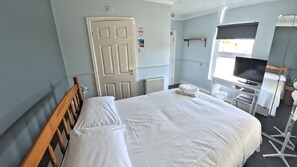 A hotel room with a large bed, a television, a desk, and a window. - Riverside Inn (Spalding)