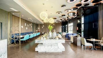 Interior moderno de restaurante con barra central de mármol, asientos azules y un diseño de techo único.
