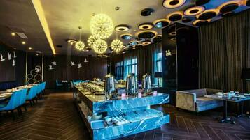A modern dining area with a marble counter, blue chairs, and a tiered seating arrangement.