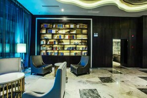 A modern lobby with a large, illuminated bookshelf, comfortable seating, and a marble floor. - Crystal Orange Hotel Changzhou Dinosaurs Park (Changzhou)