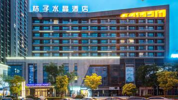 A multi-story hotel with a modern facade, large windows, and a prominent signage for the Crystal Orange Hotel.