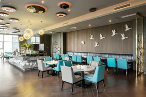 A modern restaurant interior with round tables, teal chairs, and a wall with bird decorations. - Crystal Orange Hotel Changzhou Dinosaurs Park (Changzhou)