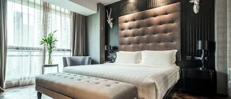 A modern bedroom with a large bed, a bench, a nightstand, and a wall-mounted animal head.