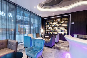 A modern hotel lobby with a large bookshelf, comfortable seating, and a reception desk. - Crystal Orange Hotel Changzhou Dinosaurs Park (Changzhou)