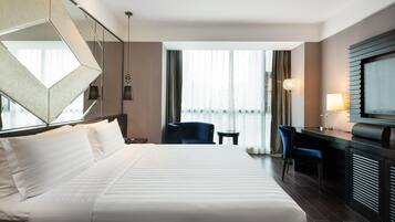A hotel room with a large bed, a desk, a chair, and a TV.