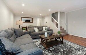 Relax in this stylish living room with a large sofa, armchair, and wooden coffee table.