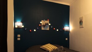 Ein Schlafzimmer mit dunkelblauer Akzentwand, einem Bett mit brauner Kopfteil und Lichterkette.