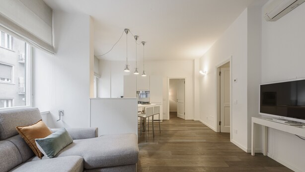 Una sala de estar moderna con un sofá seccional gris, un televisor de pantalla plana y piso de madera.
