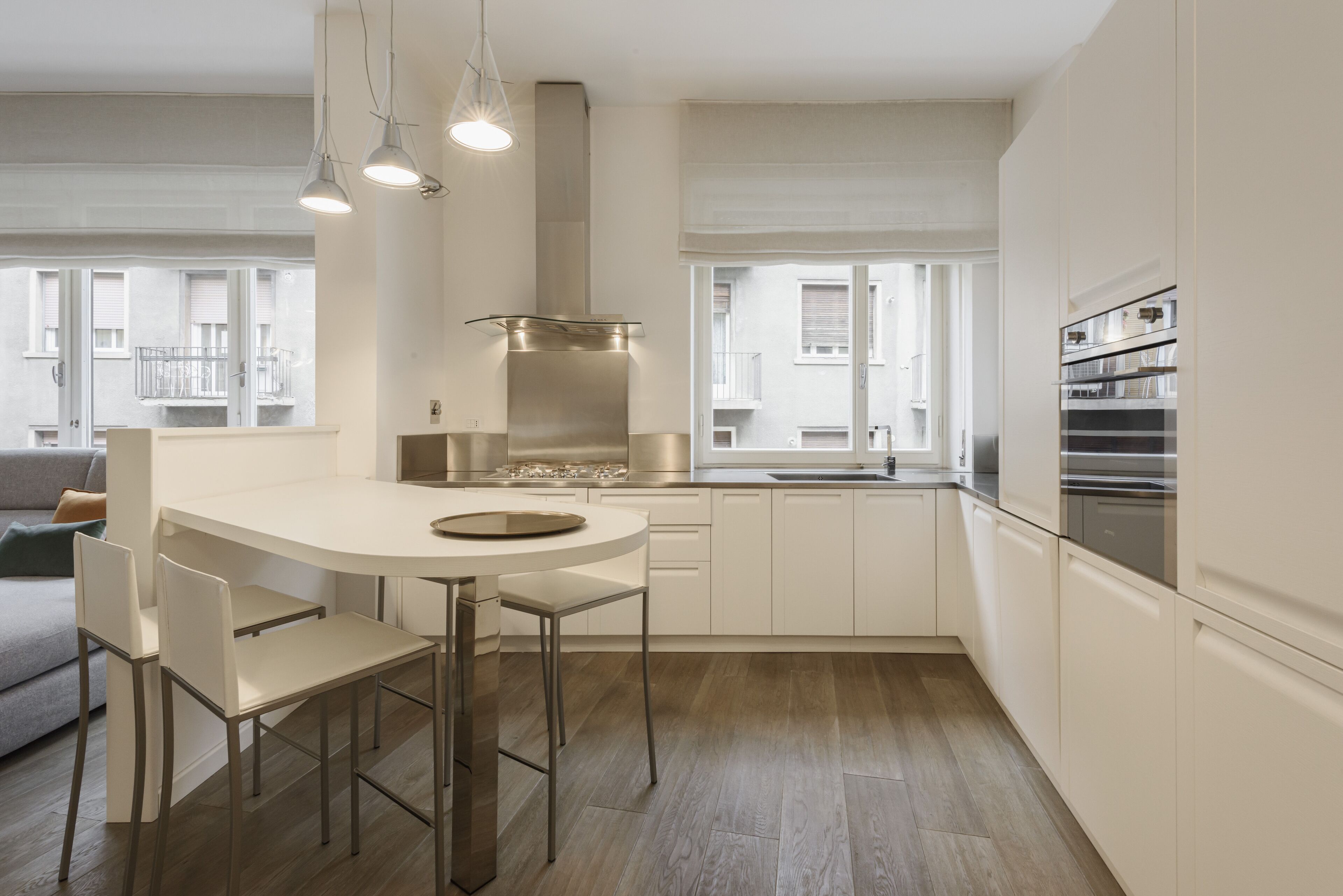 Une cuisine moderne dotée d’un îlot central, d’appareils électroménagers en acier inoxydable et offrant une vue sur la ville grâce à de grandes fenêtres.
