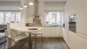 Una cocina moderna con una isla central, electrodomésticos de acero inoxidable y vistas de la ciudad a través de amplios ventanales.