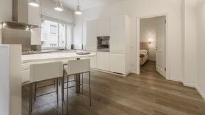 Una cocina moderna con armarios blancos, electrodomésticos de acero inoxidable y una zona de bar con taburetes.