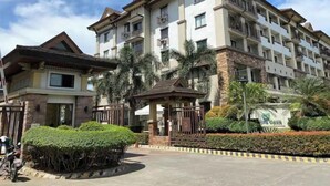 A multi-story hotel with balconies, a gated entrance, and a landscaped garden. - Spacious Condo 1BR with Washer near SM Mall (Davao City)