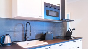 A modern kitchen with a white sink, a blue countertop, a kettle, a toaster, and a built-in oven. - Lemon Apartment With Garden and Sea View by Wonderful Italy (Bordighera)