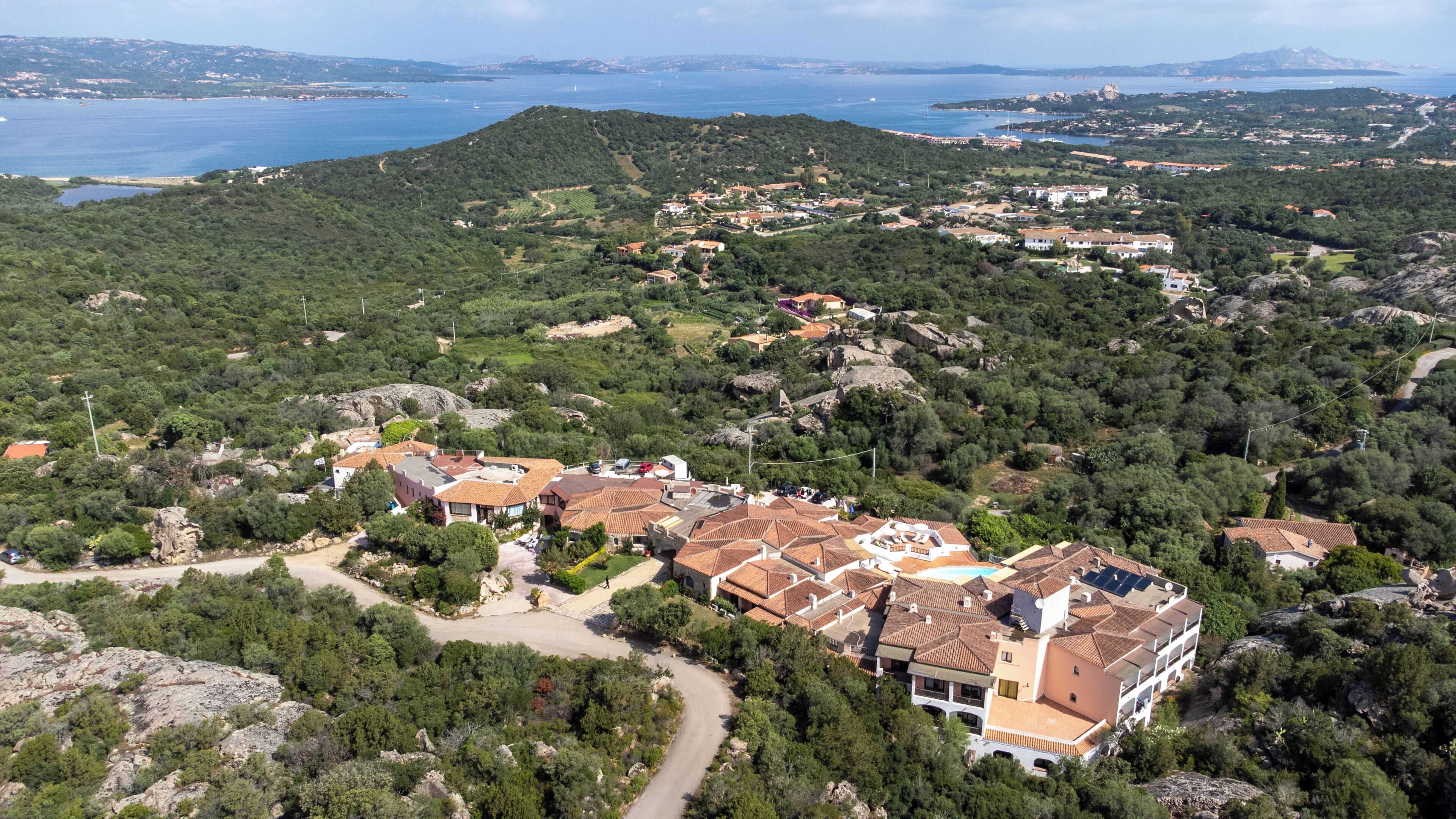 A coastal village with terraced houses, a winding road, and a view of the sea.