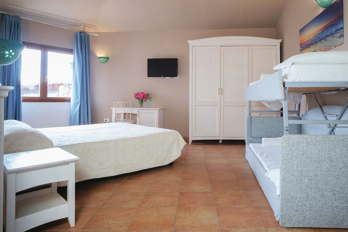 A bedroom with a bed, a desk, a chair, a wardrobe, and a bunk bed.