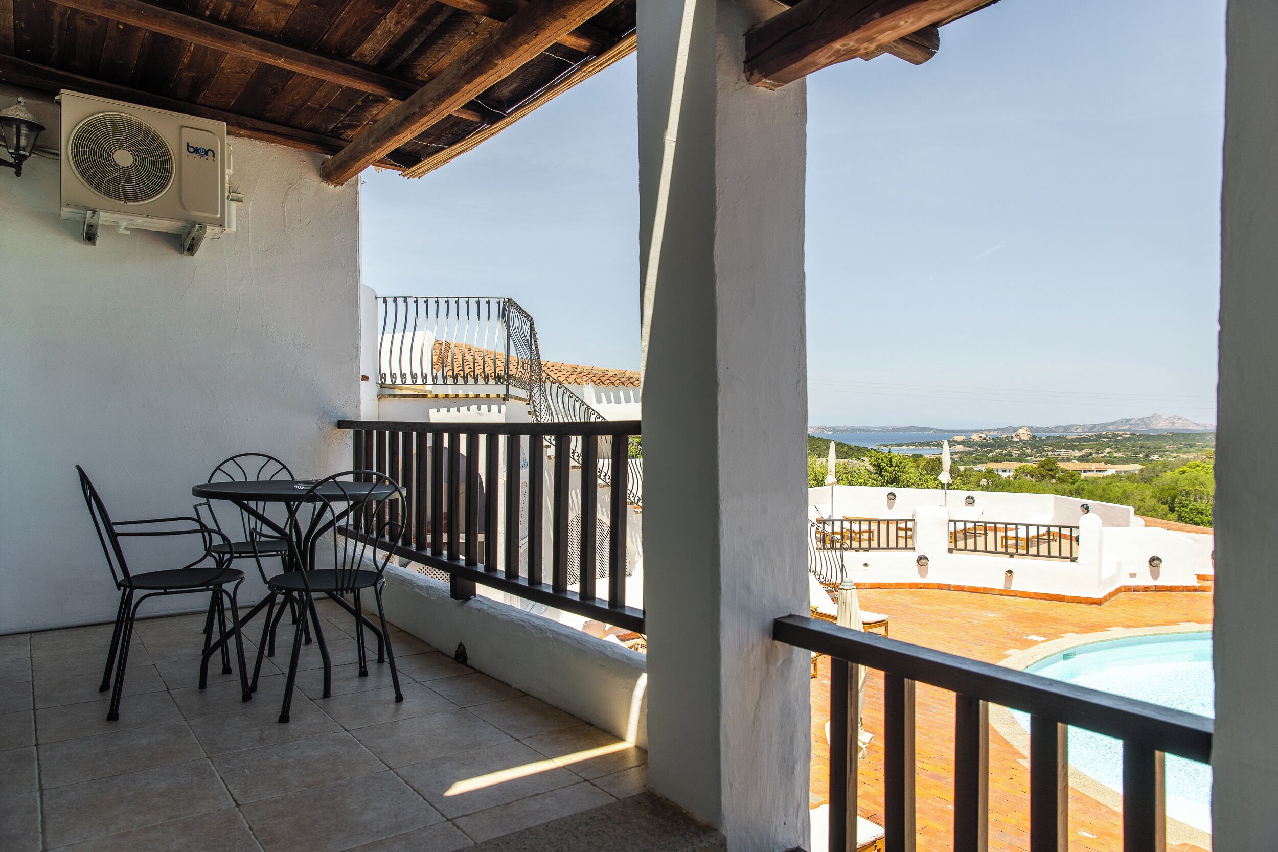 A balcony with a pool, outdoor furniture, and a view of the landscape.