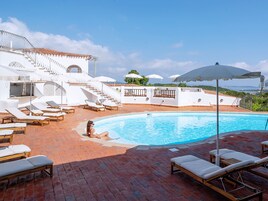 Una piscina al aire libre, sillones reclinables de piscina
