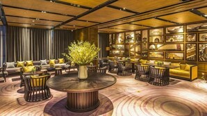 Un salón moderno con una mesa redonda central, sofás y sillones distribuidos a su alrededor.