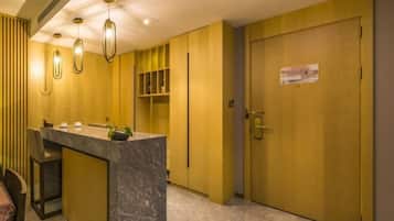 A hotel lobby with a marble reception desk, pendant lighting, and a closed door with a sign.
