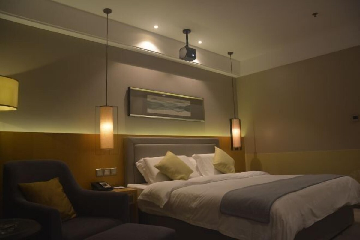 A hotel room with a bed, bedside lamps, a chair, and a nightstand.
