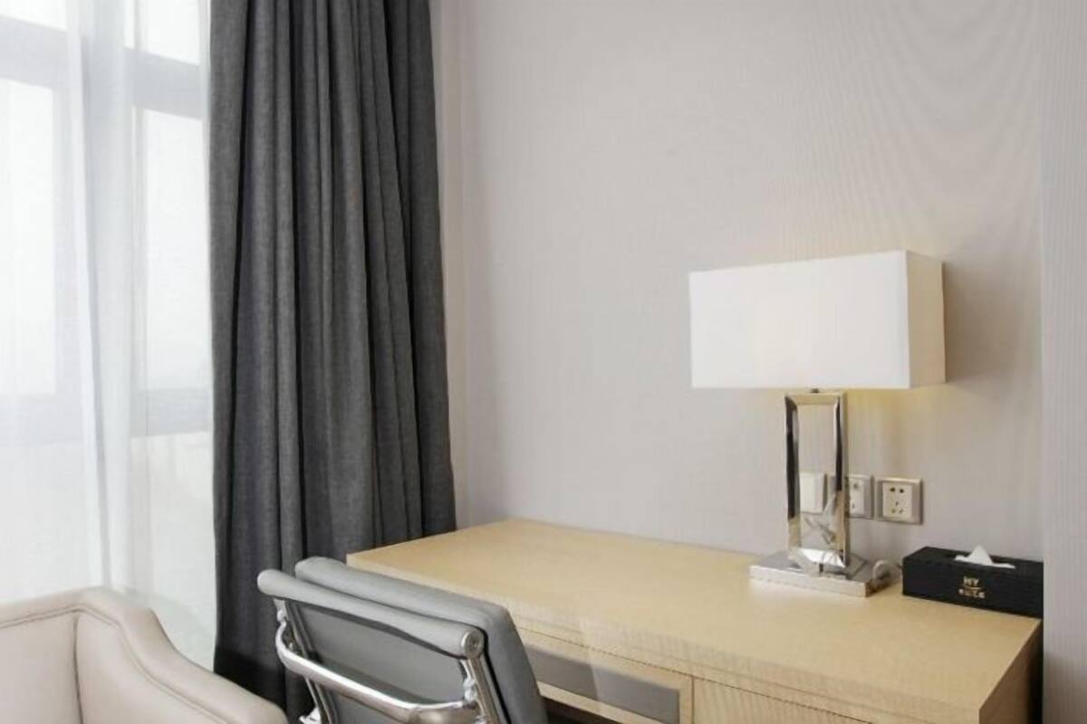A hotel room with a desk, chair, lamp, and a box labeled 'NY RULES'.